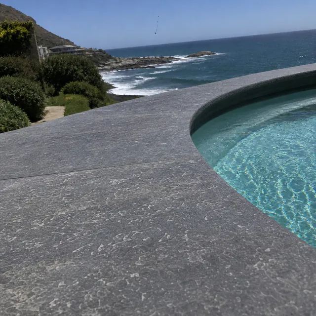 Slate bullnose coping along a pool edge, with the deck surface falling away from the water